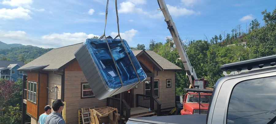 Hot tub lifted by crane over a Smoky Mountain cabin to be set on the deck