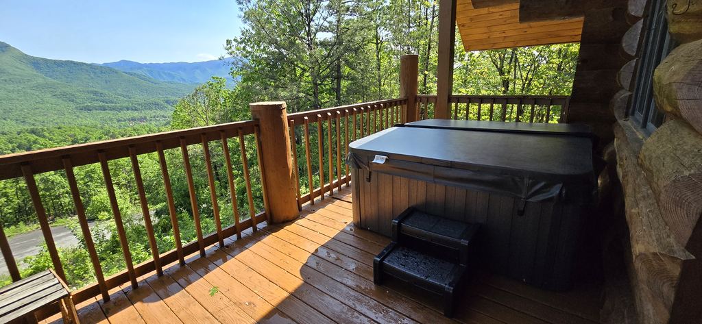 Hot tub with its cover on and steps on a cabin deck overlooking the mountains