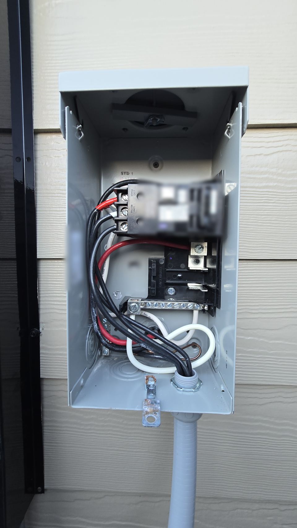 New outdoor spa disconnect box with a breaker and wiring, mounted on a house wall