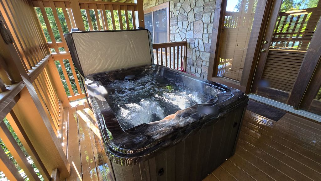 Hot tub with the jets running on a covered cabin deck next to a stone wall