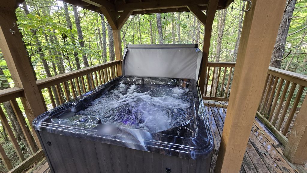 Hot tub with the jets running under a wooden gazebo in the woods