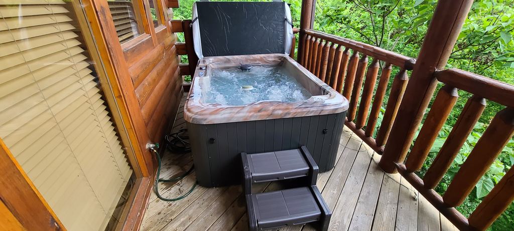 Two-person hot tub with steps on a wooded cabin porch