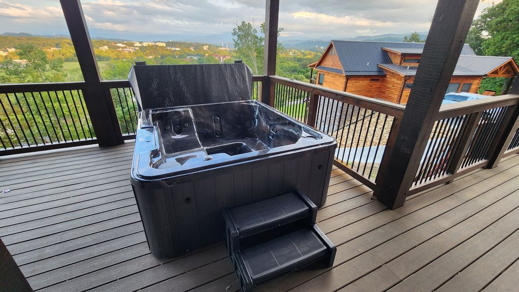 Hot tub with steps on a covered deck overlooking the valley