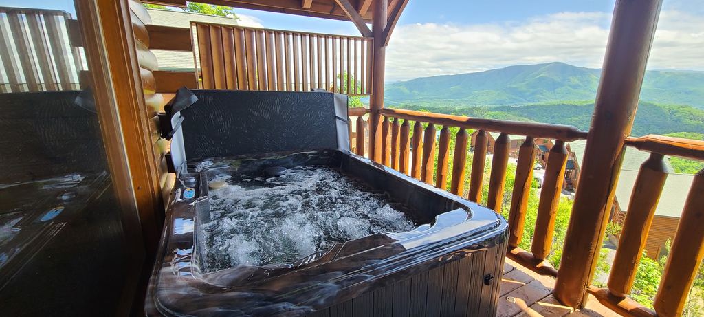 Hot tub with the jets running on a log cabin deck with mountain views