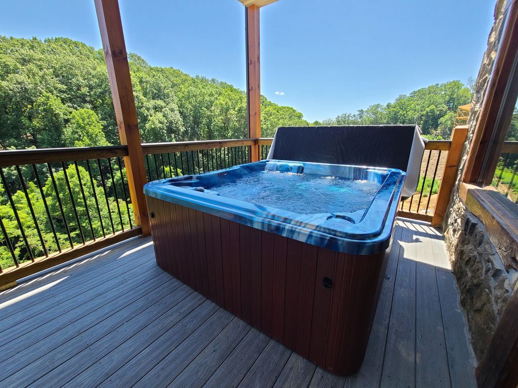 New hot tub with a blue marbled shell and the jets running on a covered cabin deck with a forest view