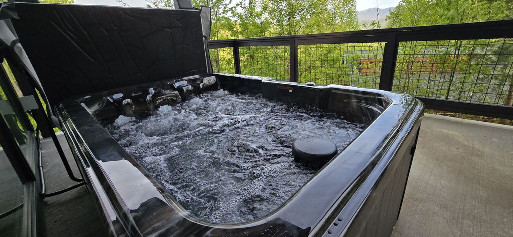 Black marbled hot tub with the jets running on a covered concrete patio
