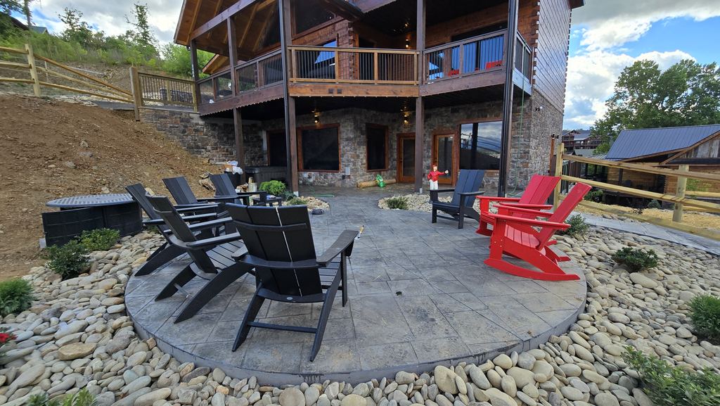 New cabin patio with a hot tub, Adirondack chairs and a river-rock fire pit area
