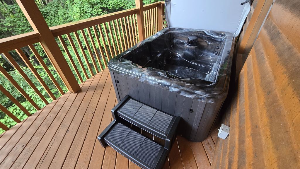 Hot tub with steps on a narrow wooded cabin deck
