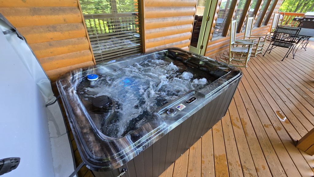 Hot tub with the jets running on a long wraparound cabin porch