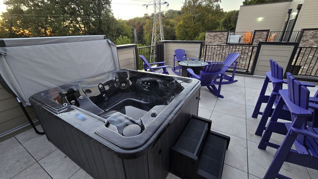 Rooftop hot tub with the cover lifted, steps and purple Adirondack chairs at dusk