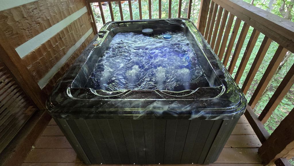 Hot tub glowing blue with the jets running on a covered cabin deck