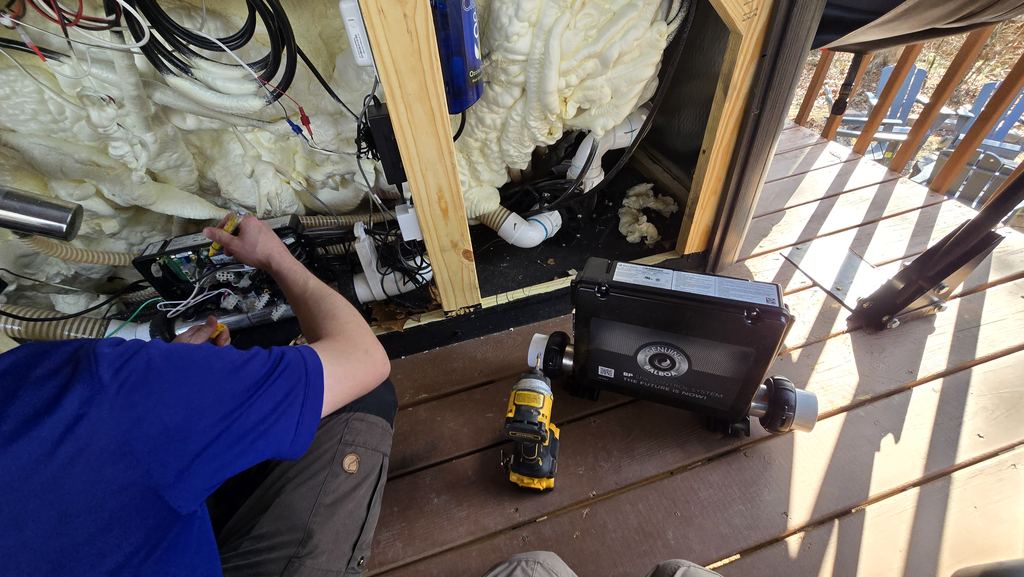 Technician replacing a hot tub control pack, with the new pack set on the deck