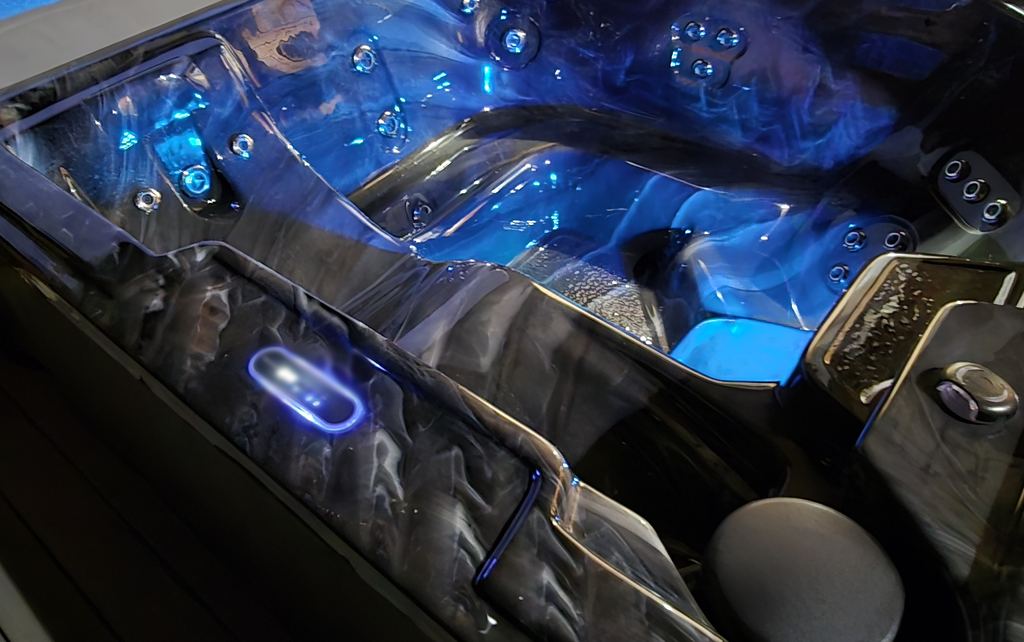 Close-up of a lit hot tub topside control, jets and blue underwater lights